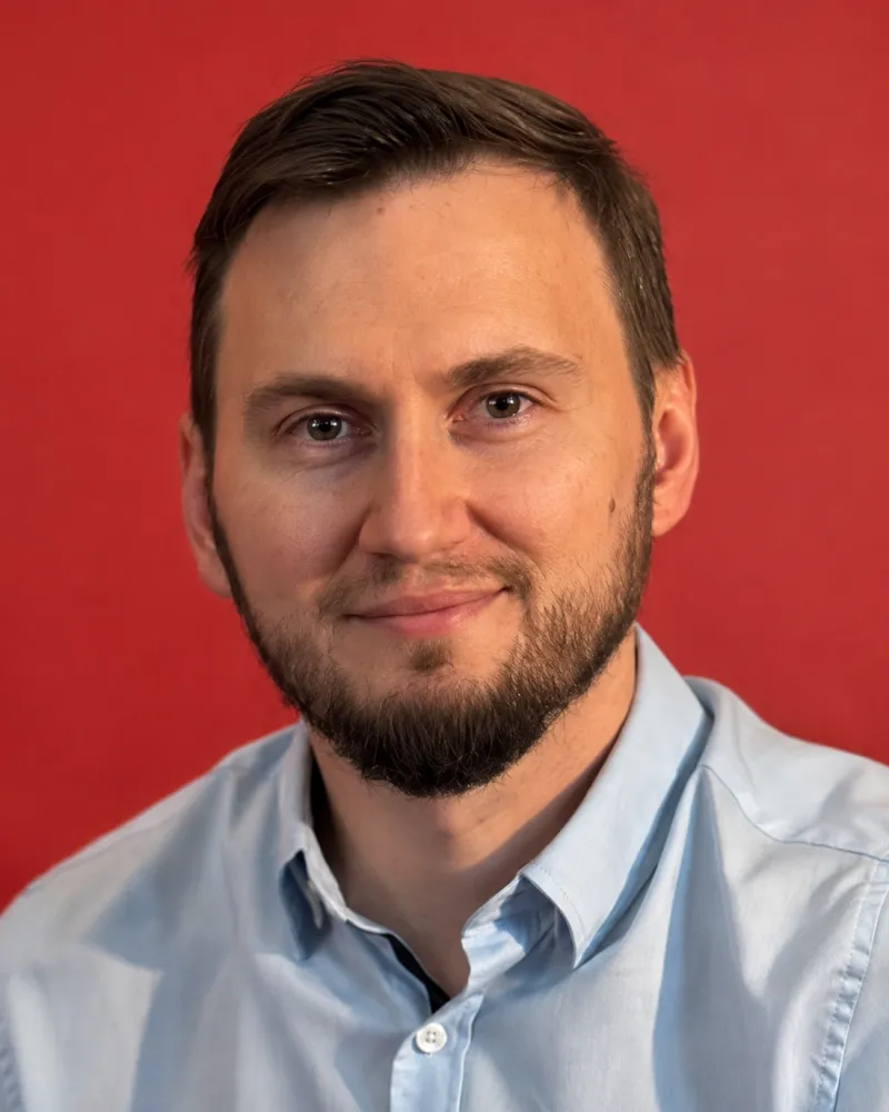 Denys Lebiediev in a light blue shirt against a red background.